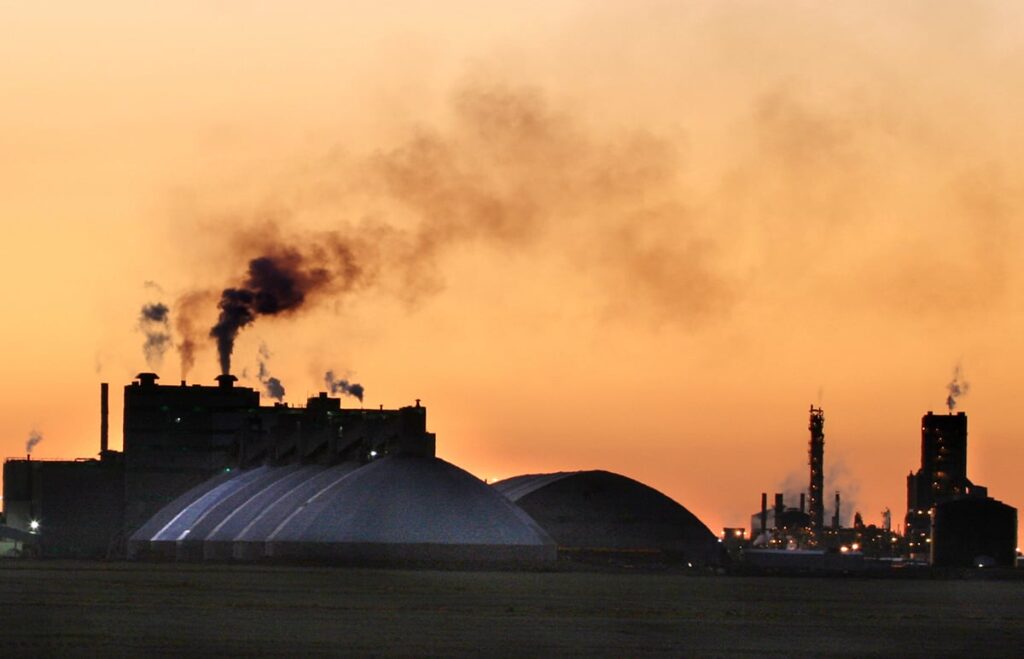 The potash mine at Belle Plaine, Saskatchewan, is silhouetted agains the orange sky at sunset.