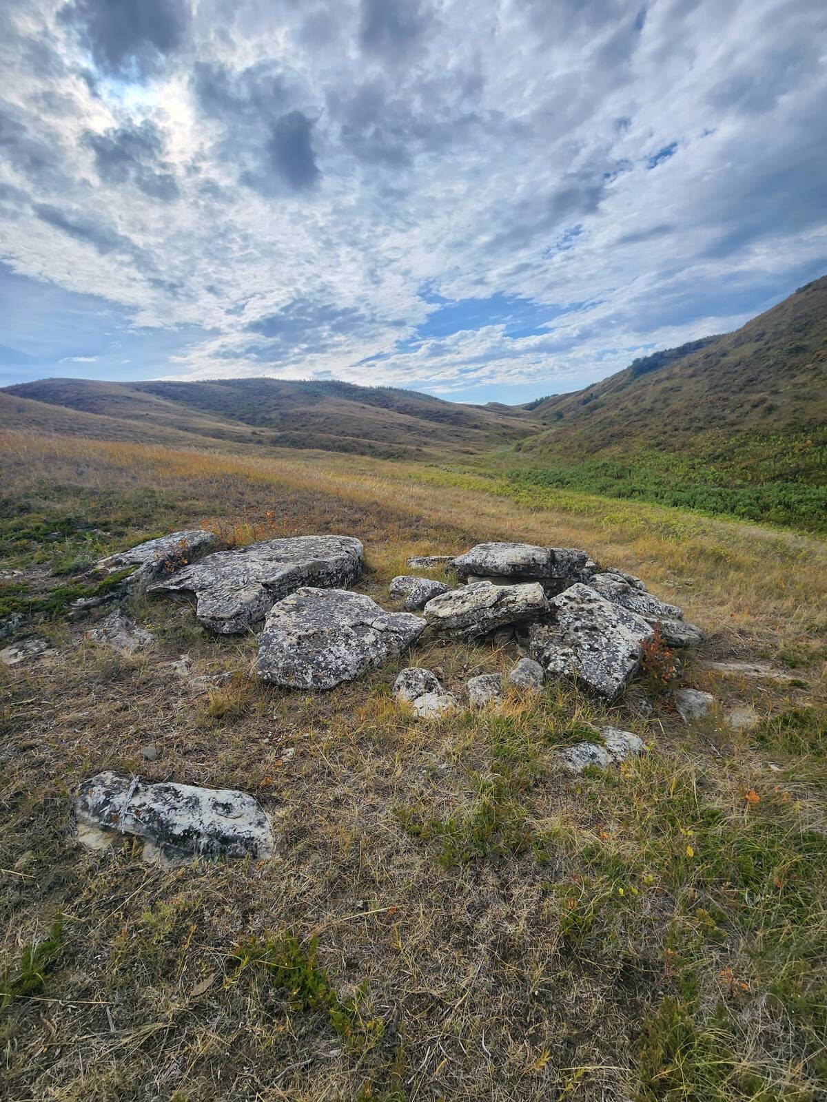 Some stones sit exposed on top of a hill with a valley snaking away into the background.