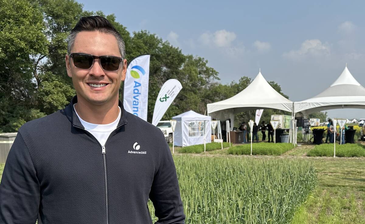 Joshua Day Chief, CEO of AdvancedAg, stands in front of a test plot wearing sun glasses at the Ag in Motion farm show near Langham, Saskatchewan on a sunny day.