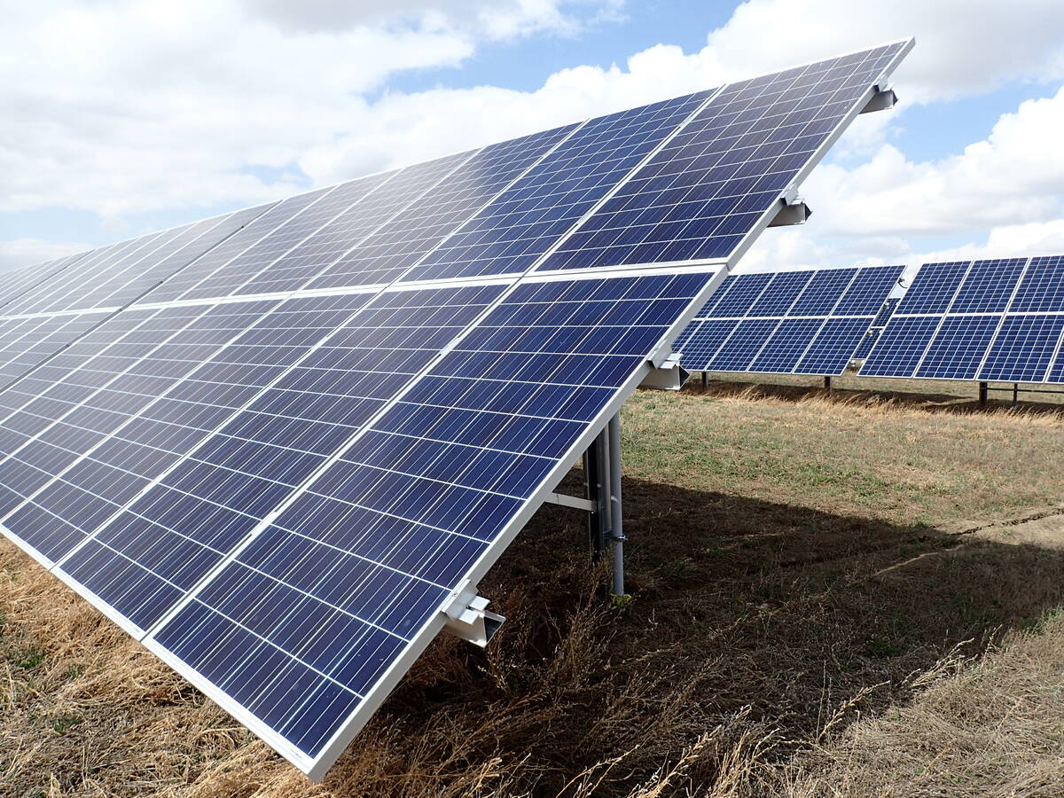 Two large arrays of solar panels are tilted upward toward the sun on a day with mixed sun and cloud.