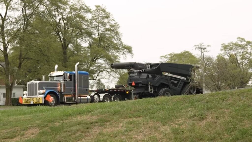 A Fendt Ideal combine sits on the trailer of a truck with a yellow 