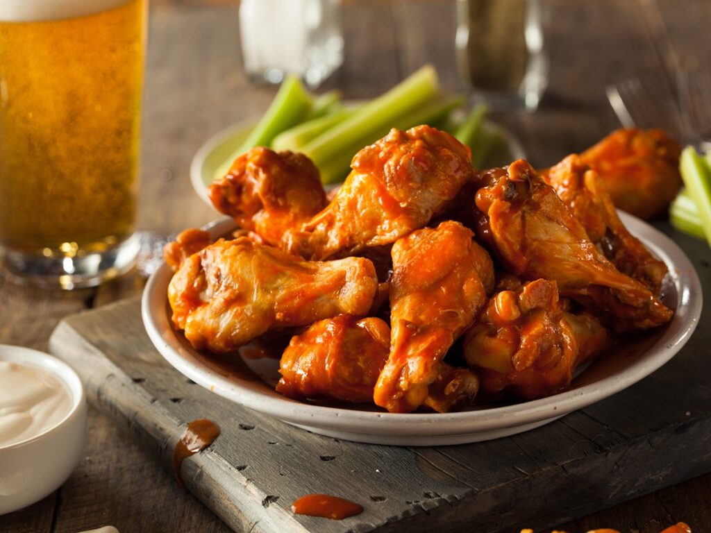 Hot wings on a plate with dip on a table in a pub.