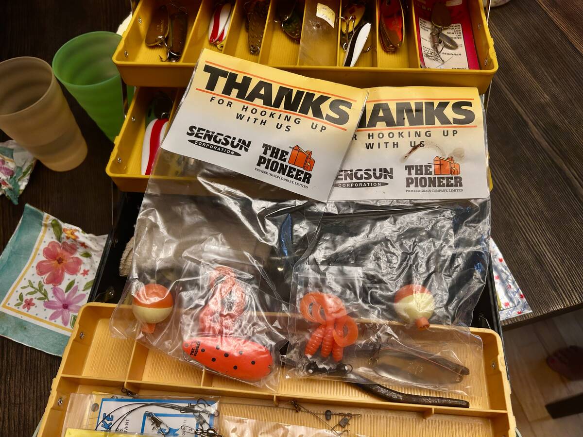 A yellow fishing tackle box sits open on a table with a number of lures in plastic bags on top with a label that reads, 