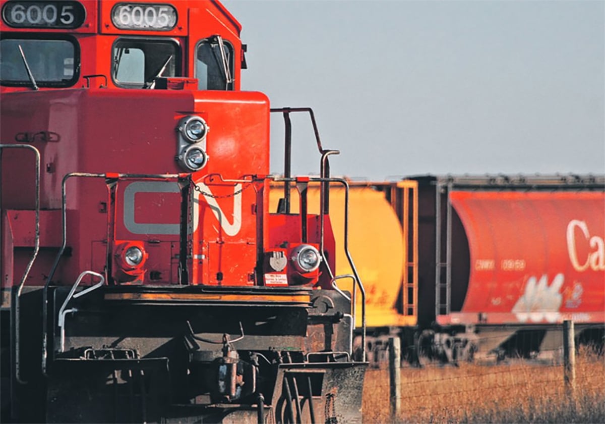 A CN train engine is in the foreground while the rest of the train can be seen in the background as it rounds a curve.