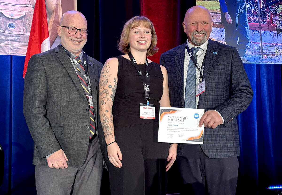 Jeff Wichtel, Dean of Ontario Veterinary College, University of Guelph, left, and George Van Kampen, Dairy Farmers of Ontario, right, present veterinarian student Lily Copp, of Wellington County, centre, and Alison Eyre, Leeds and Grenville County, not pictured, with a ,000 grant during the Ontario Federation of Agriculture’s annual general meeting, Nov. 25, 2025. Photo: Diana Martin