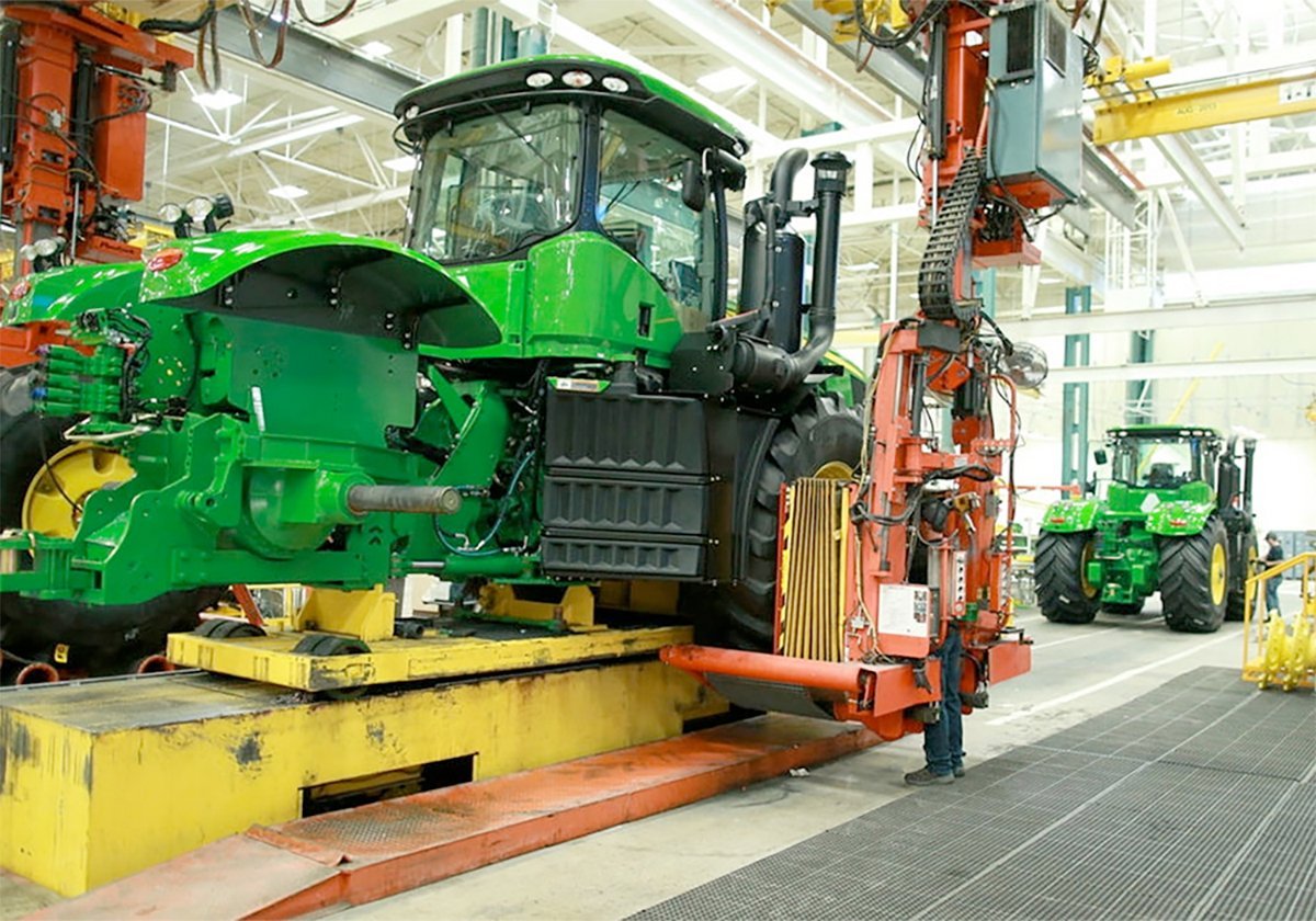A large John Deere tractor moves along the assembly line in a tractor factory.