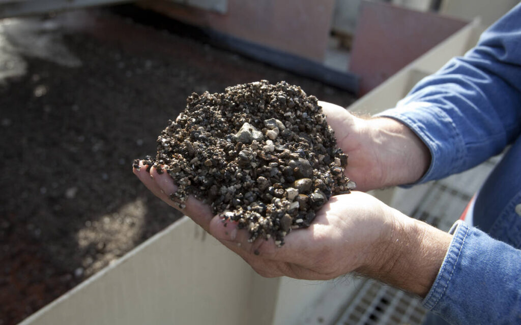 A man holds phosphate pebbles in his cupped hands.