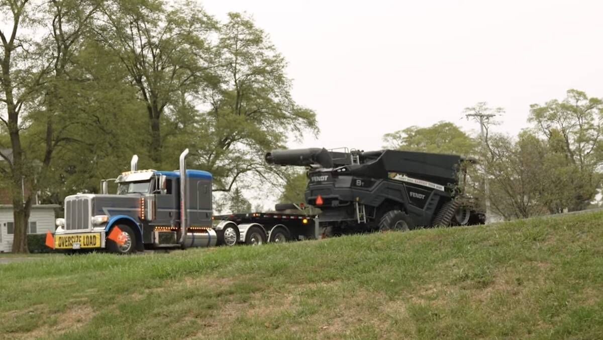 A Fendt Ideal combine sits on the trailer of a truck with a yellow 