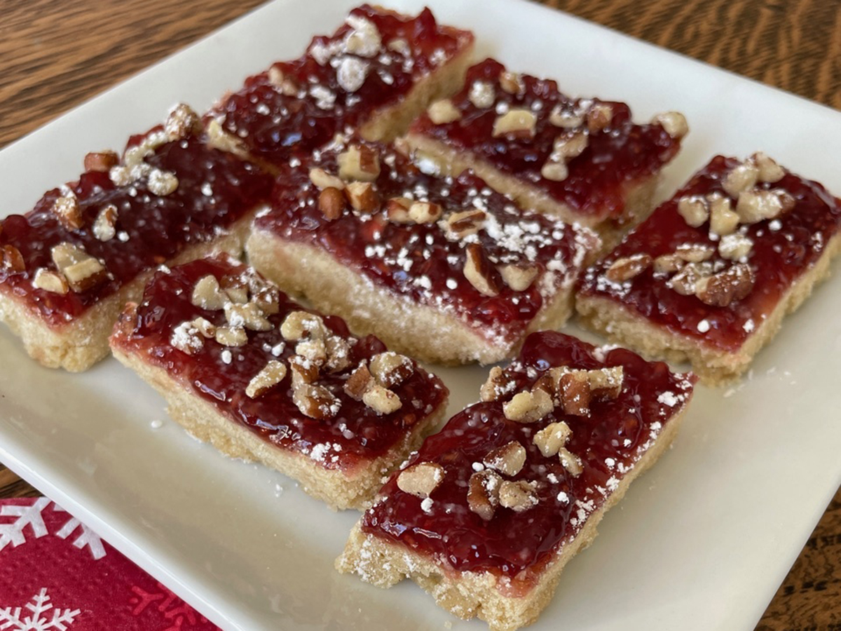 Slices of a baked pastry with a jam-like icing on top sit on a white plate.