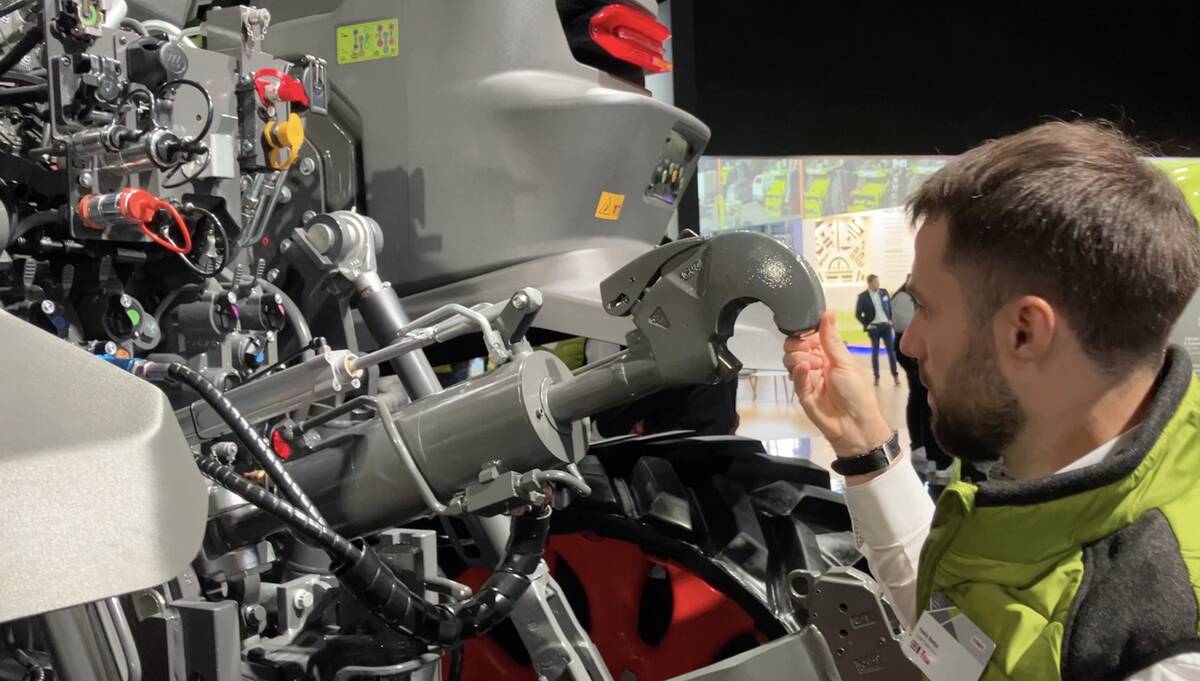 A man lifts up on the top link of a new Claas Axiom tractor at Agritechnica showing that it takes only two fingers to do so as the link has a weight compensator mechanism.