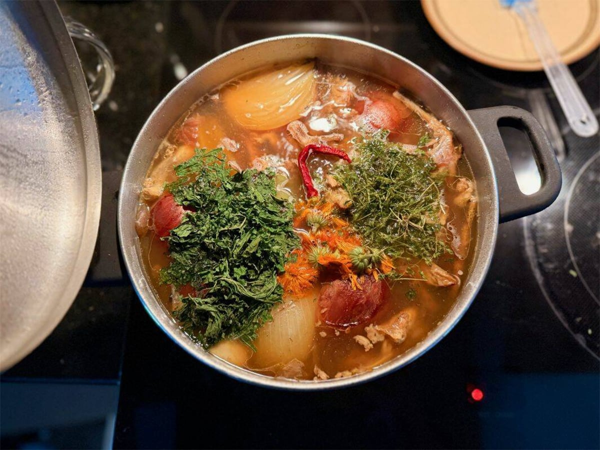 A variety of vegetables can be seen looking down into a large pot of soup.