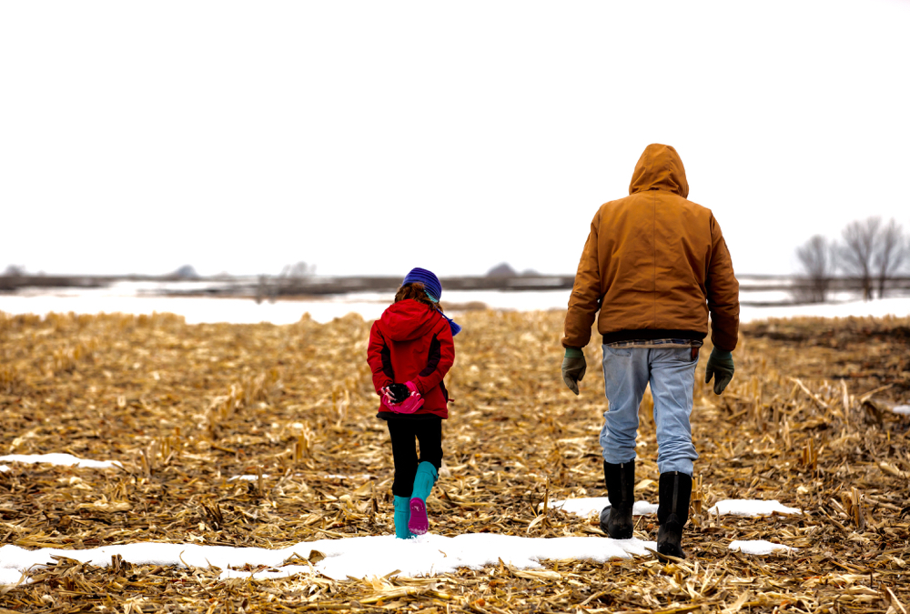A farmer and a child walk in a field.