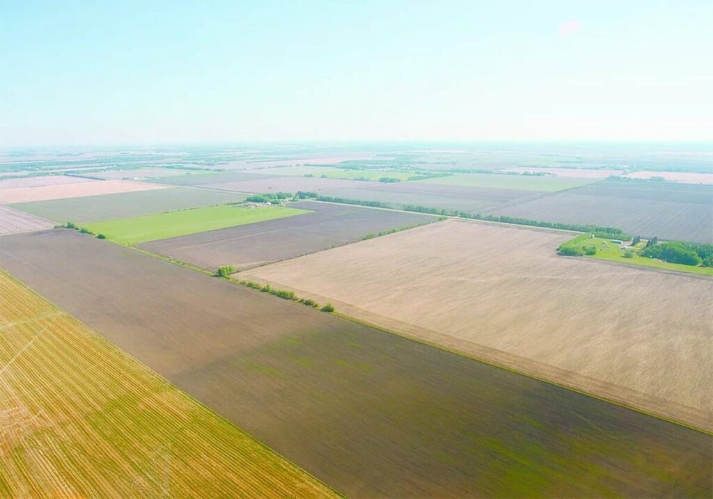 An aerial view of farmland highlighting the checkerboard effect caused by various crops.