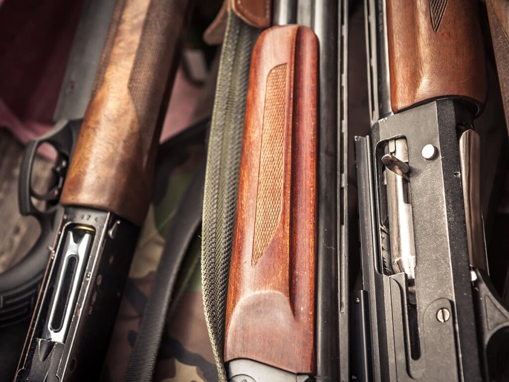 A close-up of the breaches of several guns, three with wooden stocks, one with a black plastic stock.