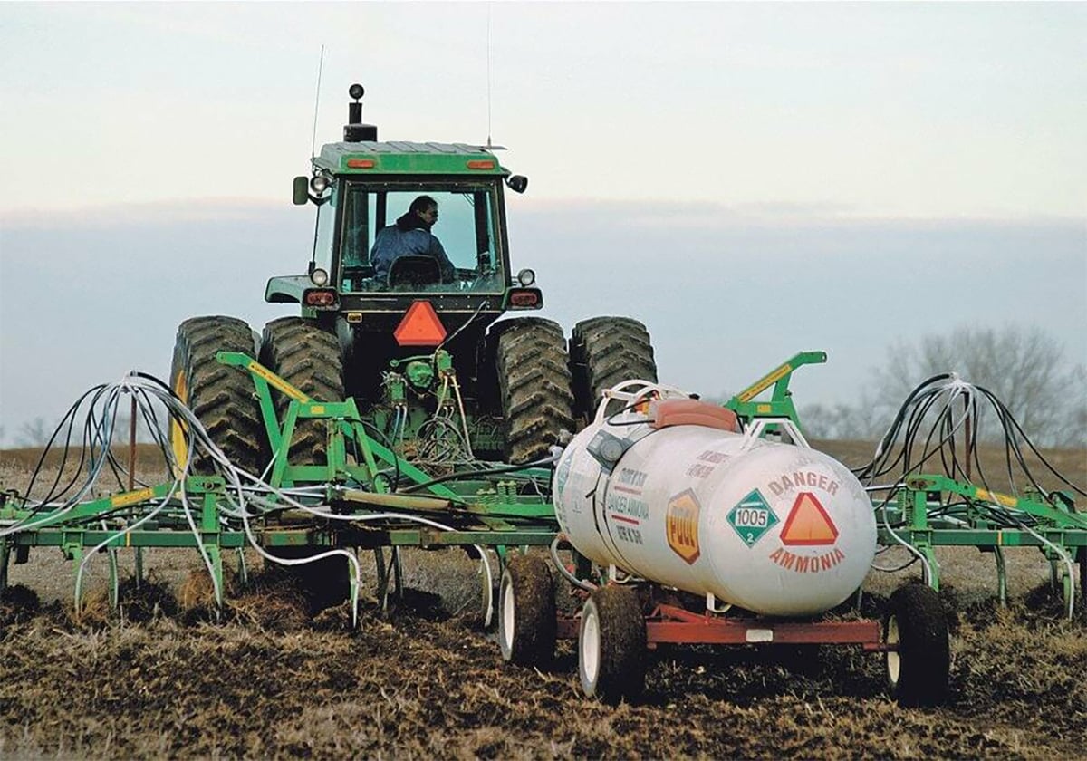 The driver of a tractor looks back over his shoulder as he applies subsurface anhydrous ammonia in a field.