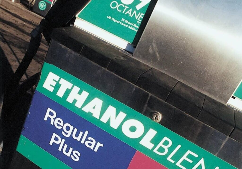 A close up of a white, green and blue sign on a gas pump that reads, 