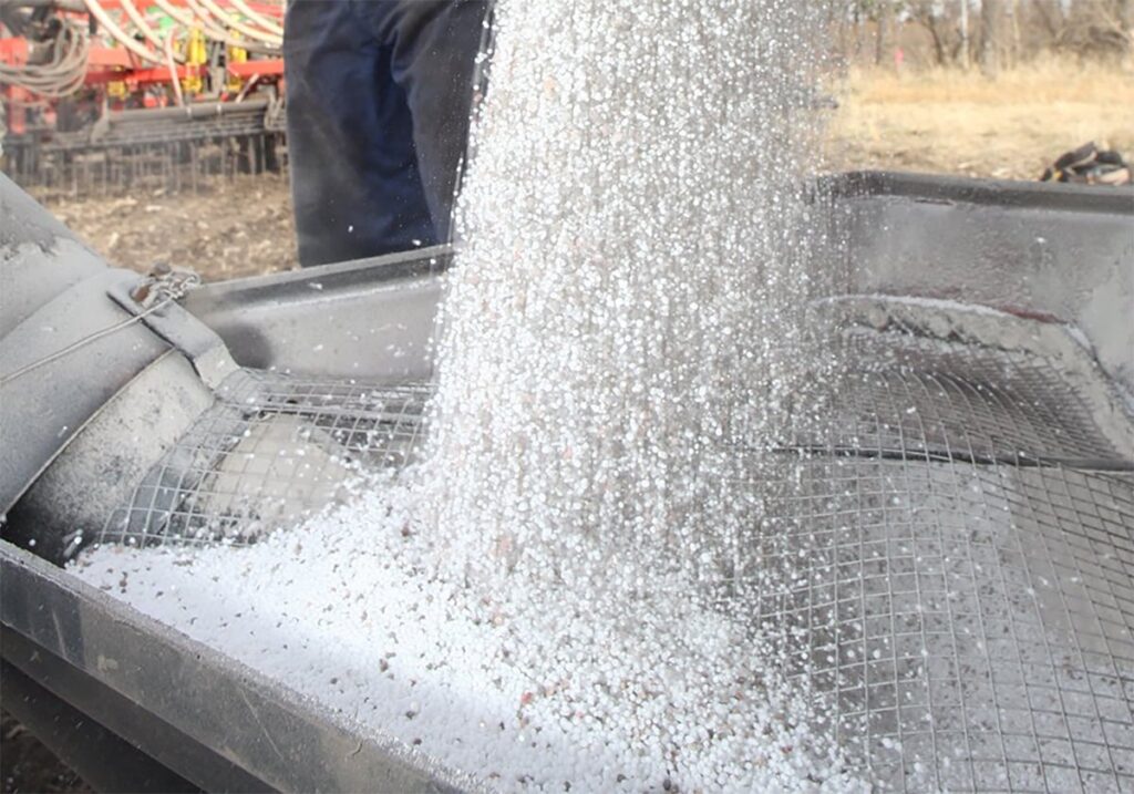 A farmer augers fertilizer from his truck.