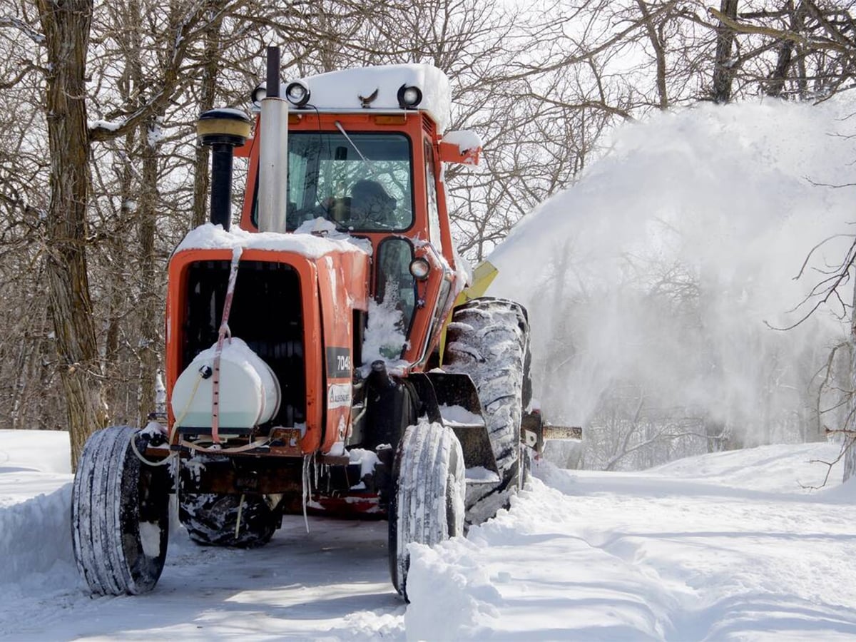 A farmer in central Manitoba blows snow out of his driveway with a tractor-mounted snowblower after a major winter storm.
