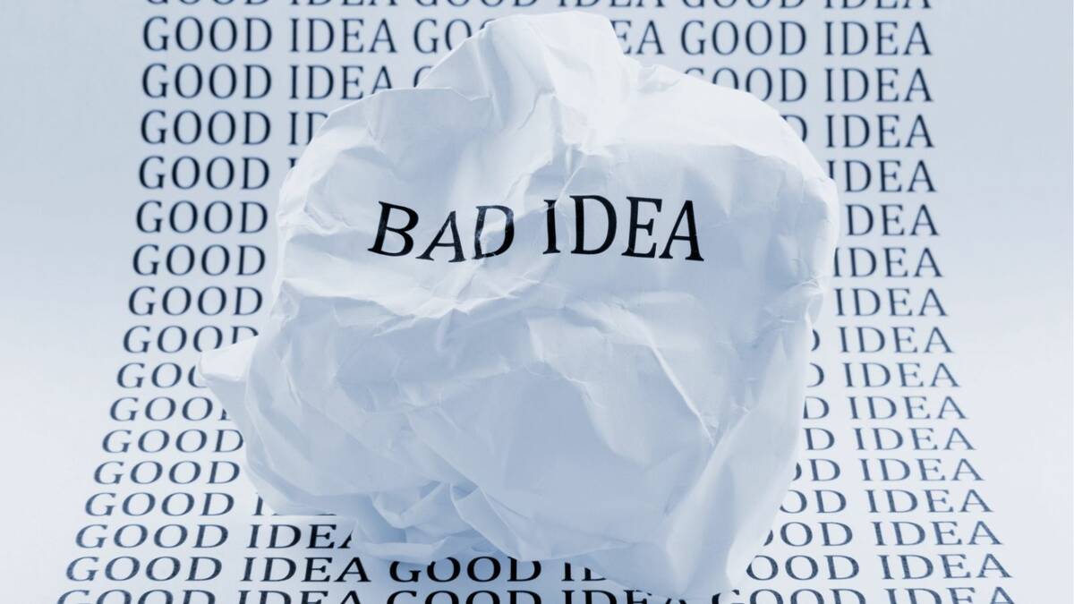 Bad idea written on a scrunched up piece of paper which is resting on a piece of paper that has good idea written all over it.