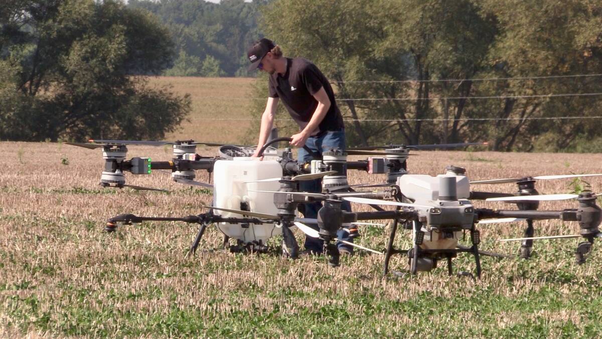 A field technician refills the spray tank of the DJI T100 drone with water after returning from a demonstration flight at the 2025 Canada’s Outdoor Farm Show.  Photo: Greg Berg