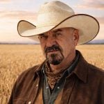 Robert Andjelic poses for a photo in front of a wheat field in the background.