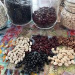 An assortment of beans on a plate and in Mason jars on a table.
