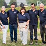The team of employees from Wilmot Orchards pose for a photo in front of some fruit bushes.