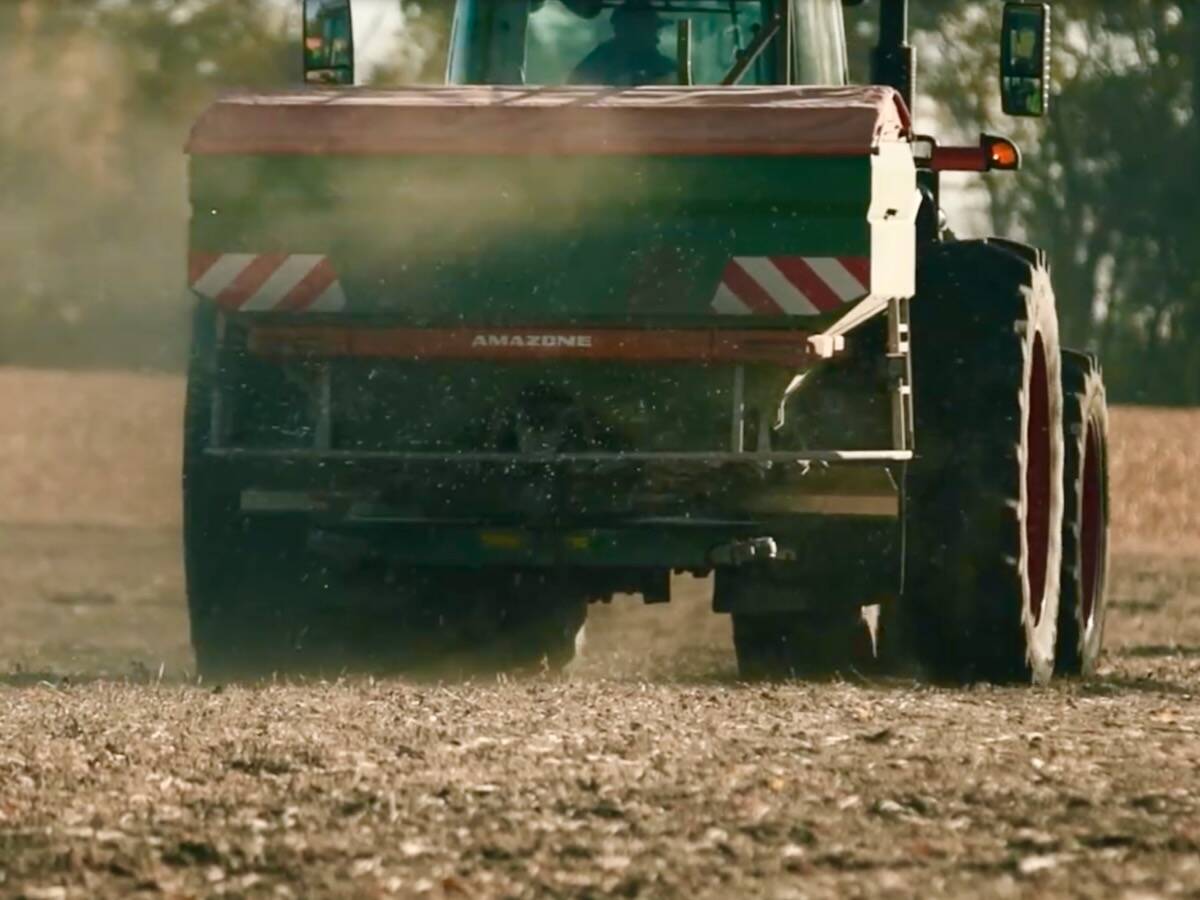 White granular fertilizer pellets fly out the back of a green Amazone ZA-TS 4201 AutoSpread unit in a farm field. Pic: Amazone North America video screengrab via YouTube