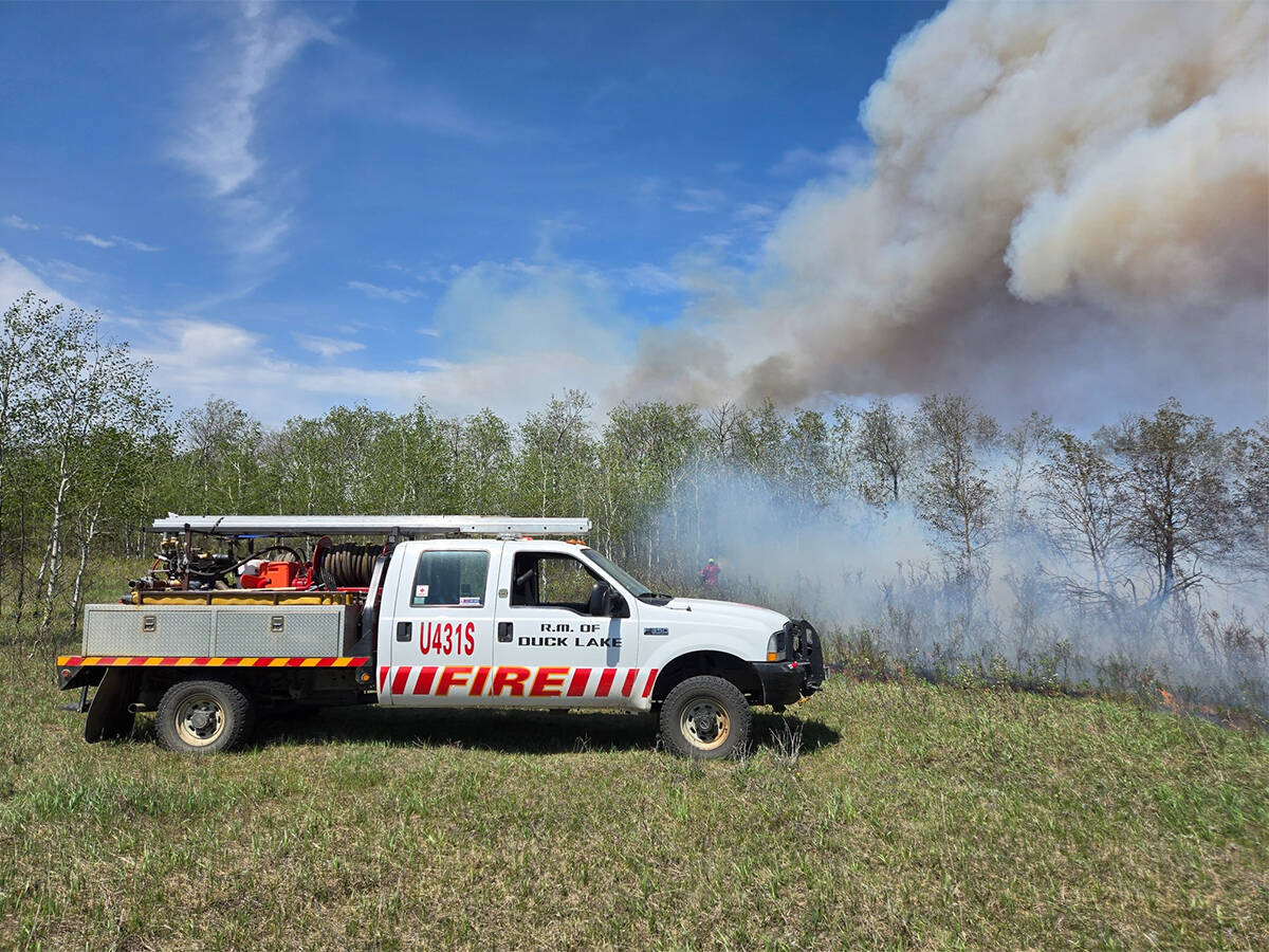 An RM of Duck Lake wildland fire truck parked on a hill with smoke rising from fire not far behind it. Photo: Facebook/Duck Lake Fire Department
