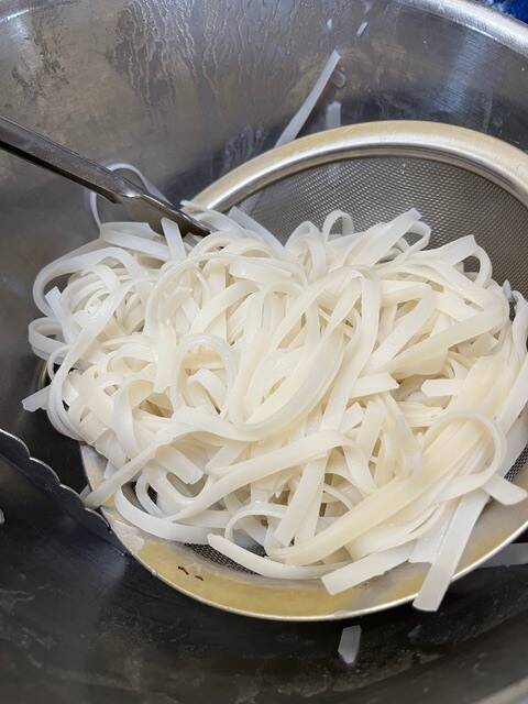 Cooked rice noodles in a strainer. 